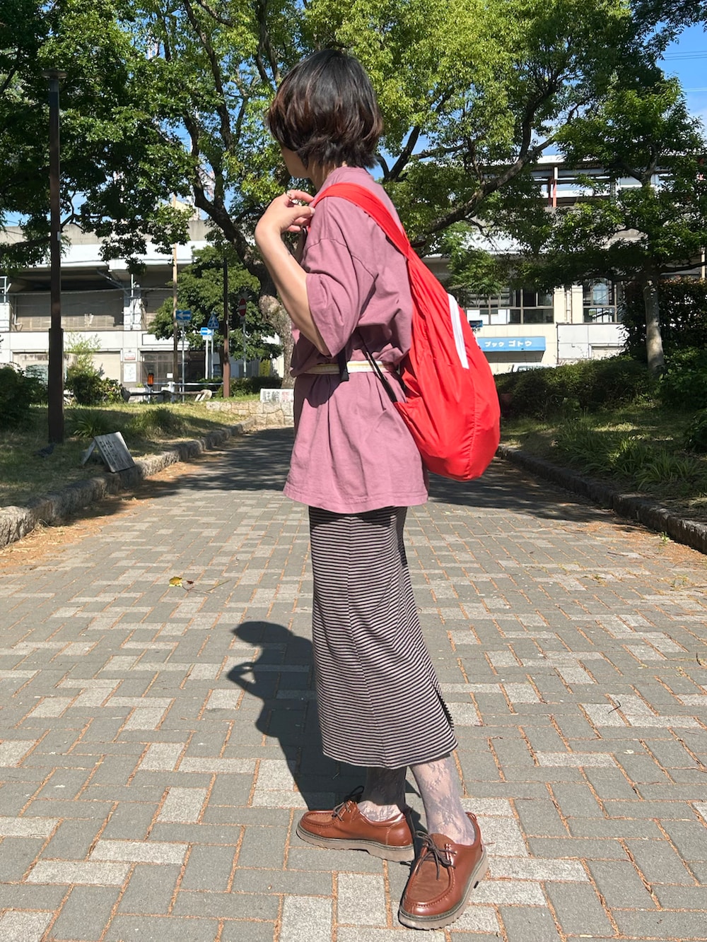 ブラウン系のワンピース、ピンク系のTシャツ/カットソー、レッド系のバックパック/リュックを着用したレディースの春コーディネートの2枚目の写真
