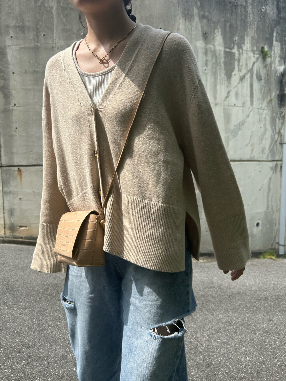 ブルー系のデニムパンツ、ベージュ系のカーディガン/ボレロ、ホワイト系のスニーカーを着用したレディースの春コーディネートの2枚目の写真