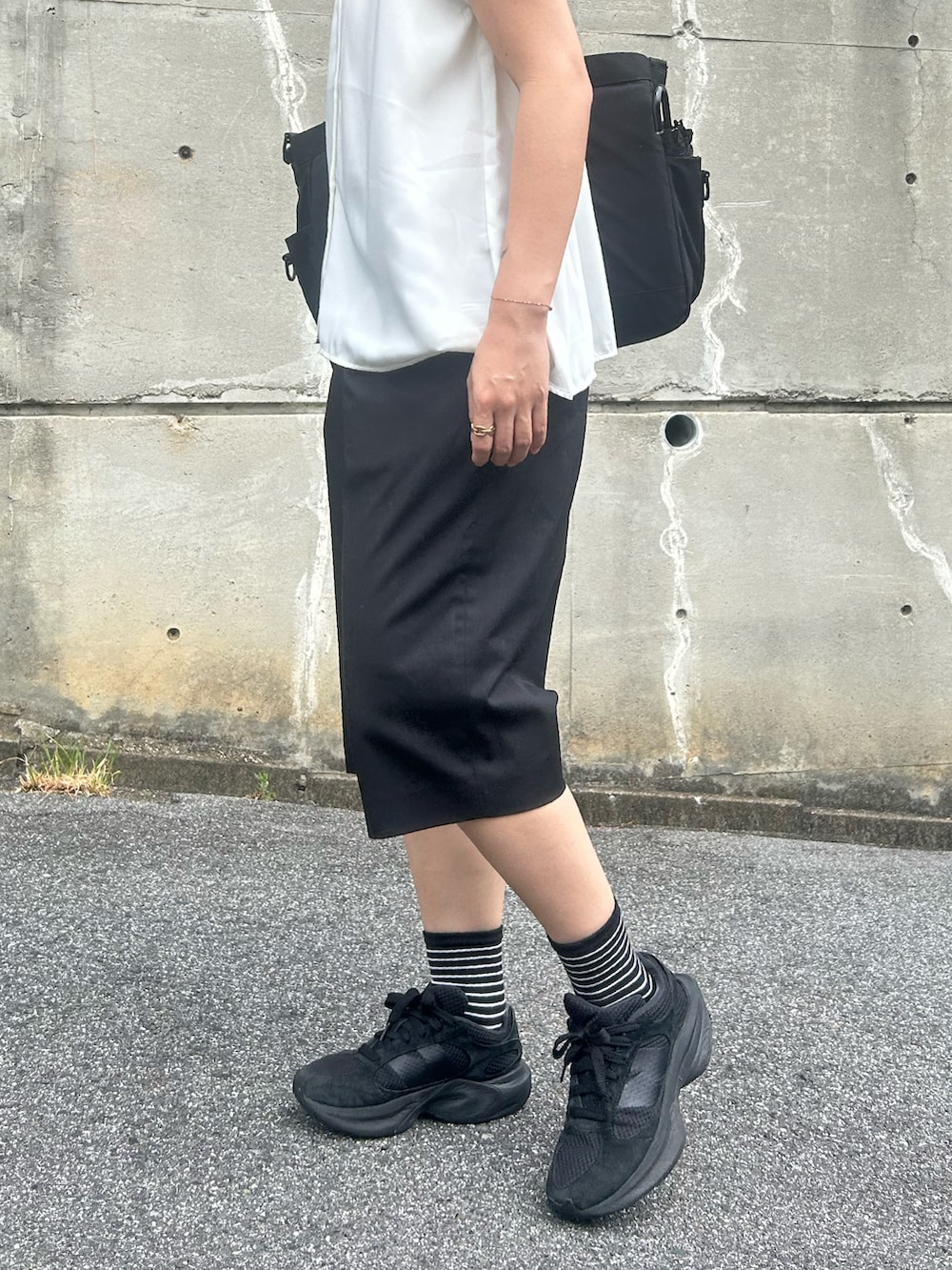 ブラック系のトートバッグ、ブラック系のスニーカー、ブラック系のパンツを着用したレディースの夏コーディネートの2枚目の写真