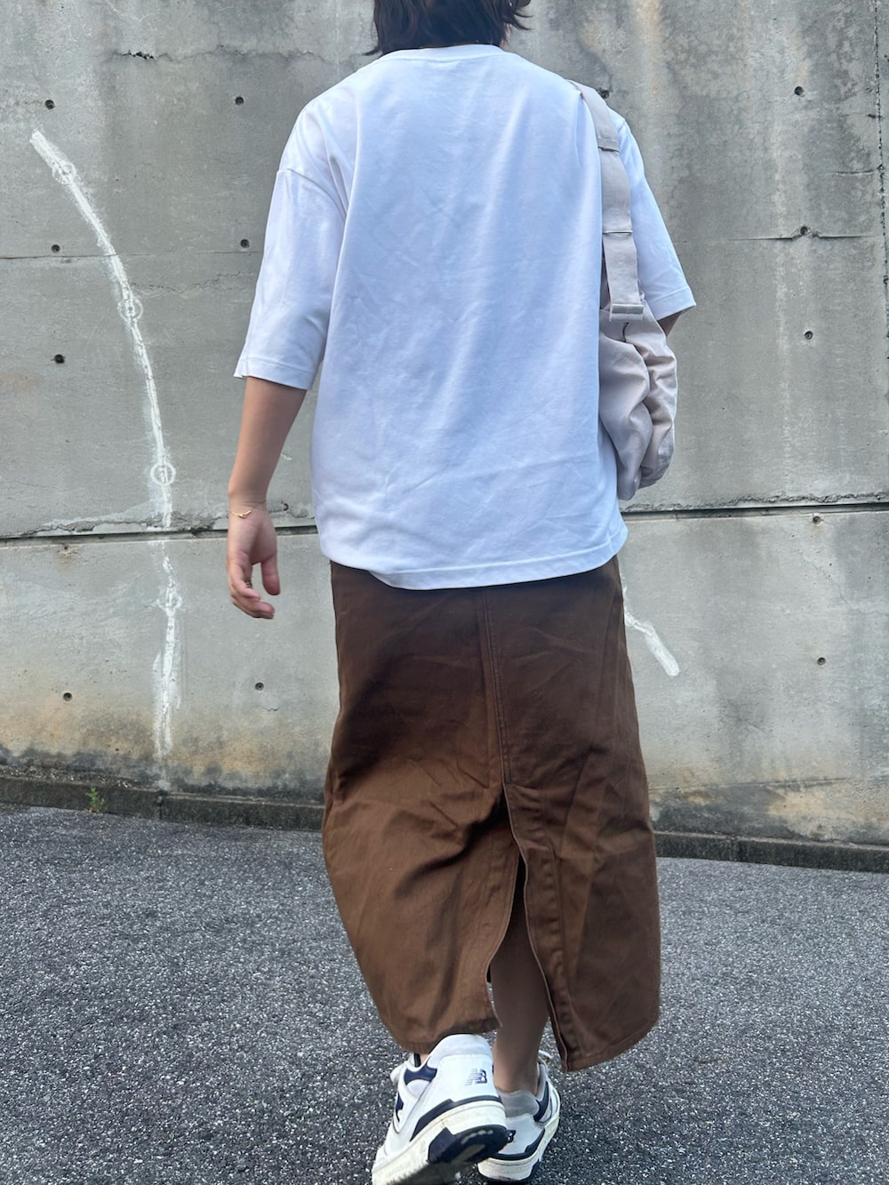 ブラウン系のデニムスカート、ホワイト系のスニーカー、ホワイト系のTシャツ/カットソーを着用したレディースの夏コーディネートの2枚目の写真