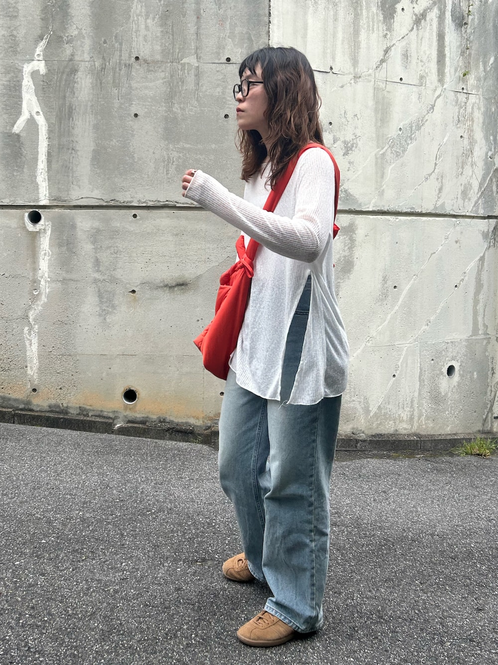 オレンジ系のトートバッグ、ブラウン系のスニーカー、ブルー系のデニムパンツを着用したレディースの春コーディネートの3枚目の写真
