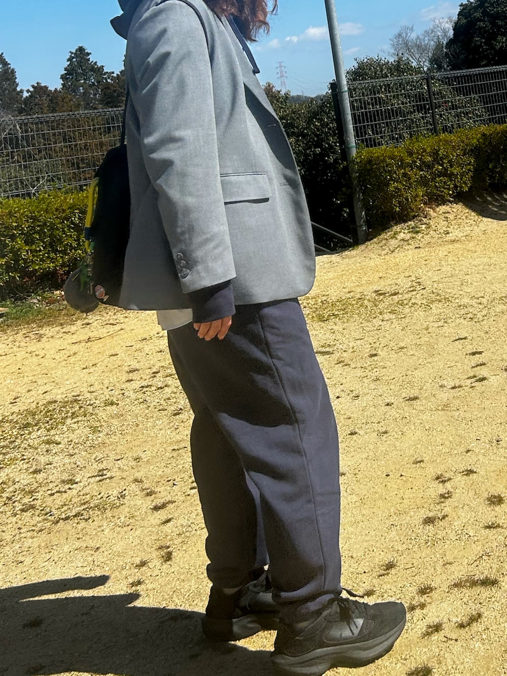 ブラック系のスニーカー、ブルー系のパーカー、グレー系のテーラードジャケットを着用したレディースの春コーディネートの4枚目の写真