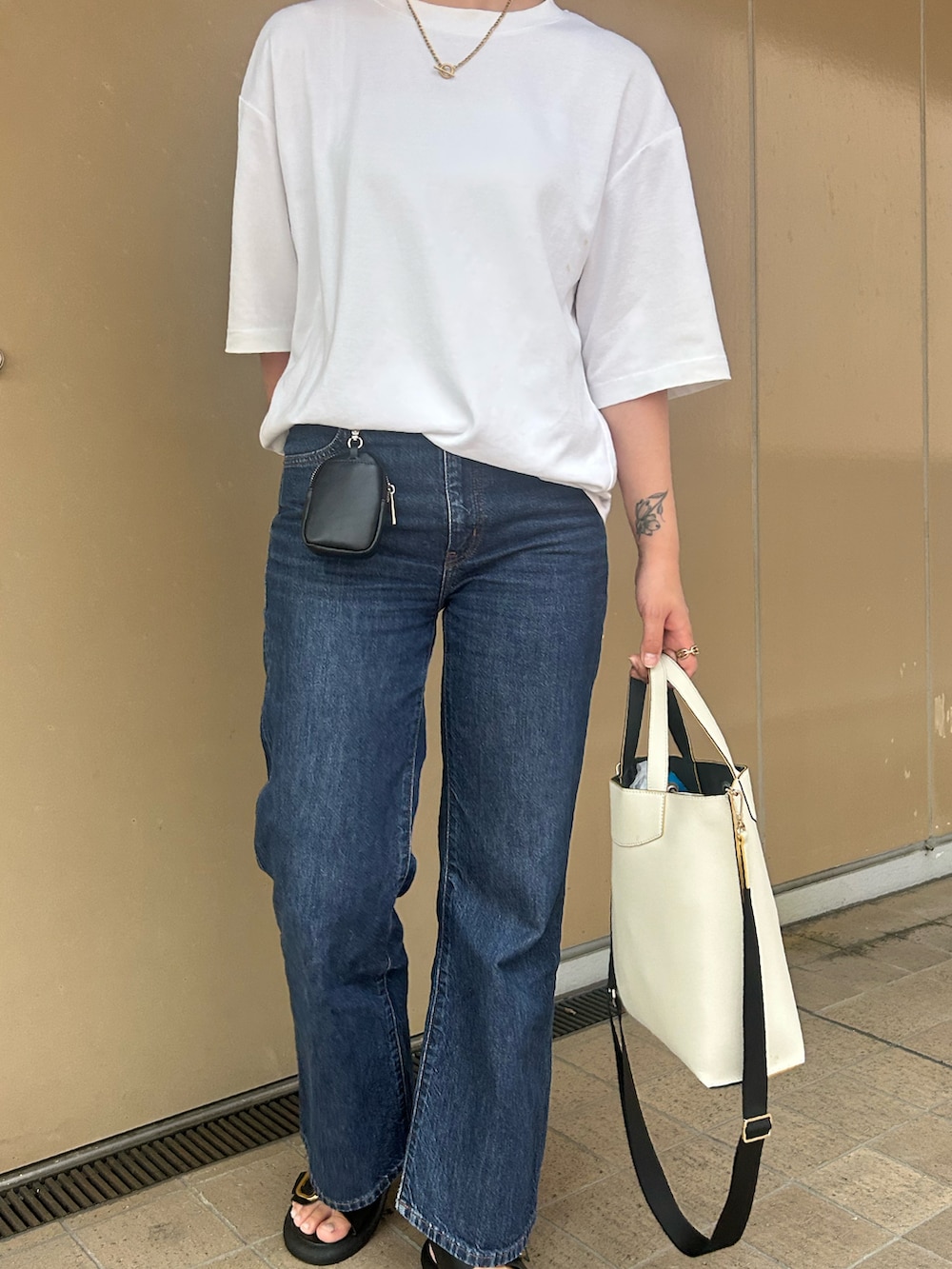 ホワイト系のTシャツ/カットソー、ブルー系のデニムパンツ、ホワイト系のハンドバッグを着用したレディースの夏コーディネートの2枚目の写真