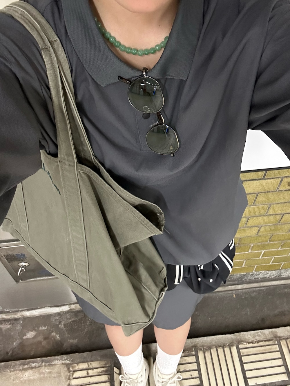ホワイト系のスニーカー、グレー系のポロシャツ、グレー系のその他パンツを着用したレディースの夏コーディネートの2枚目の写真