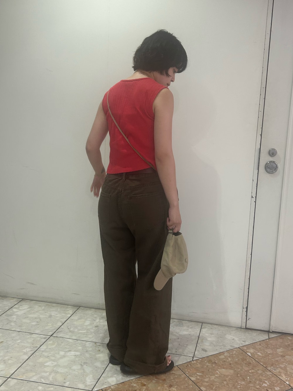 レッド系のTシャツ/カットソー、ブラウン系のデニムパンツ、ブラック系のサンダルを着用したレディースの夏コーディネートの2枚目の写真