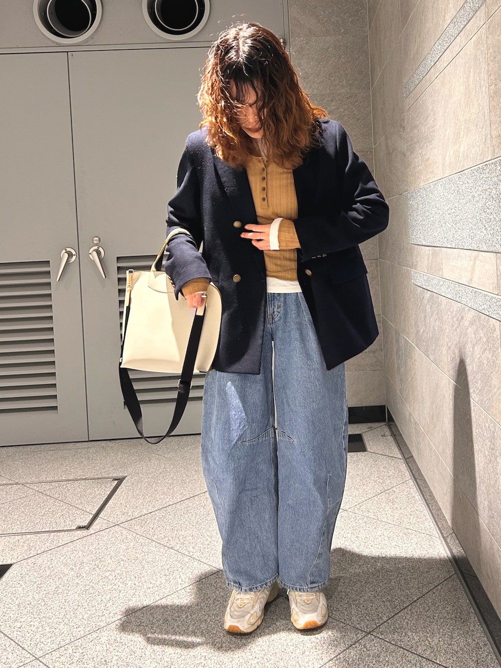 ベージュ系のトップス、ブルー系のテーラードジャケット、ブルー系のデニムパンツを着用したレディースの春コーディネートの2枚目の写真