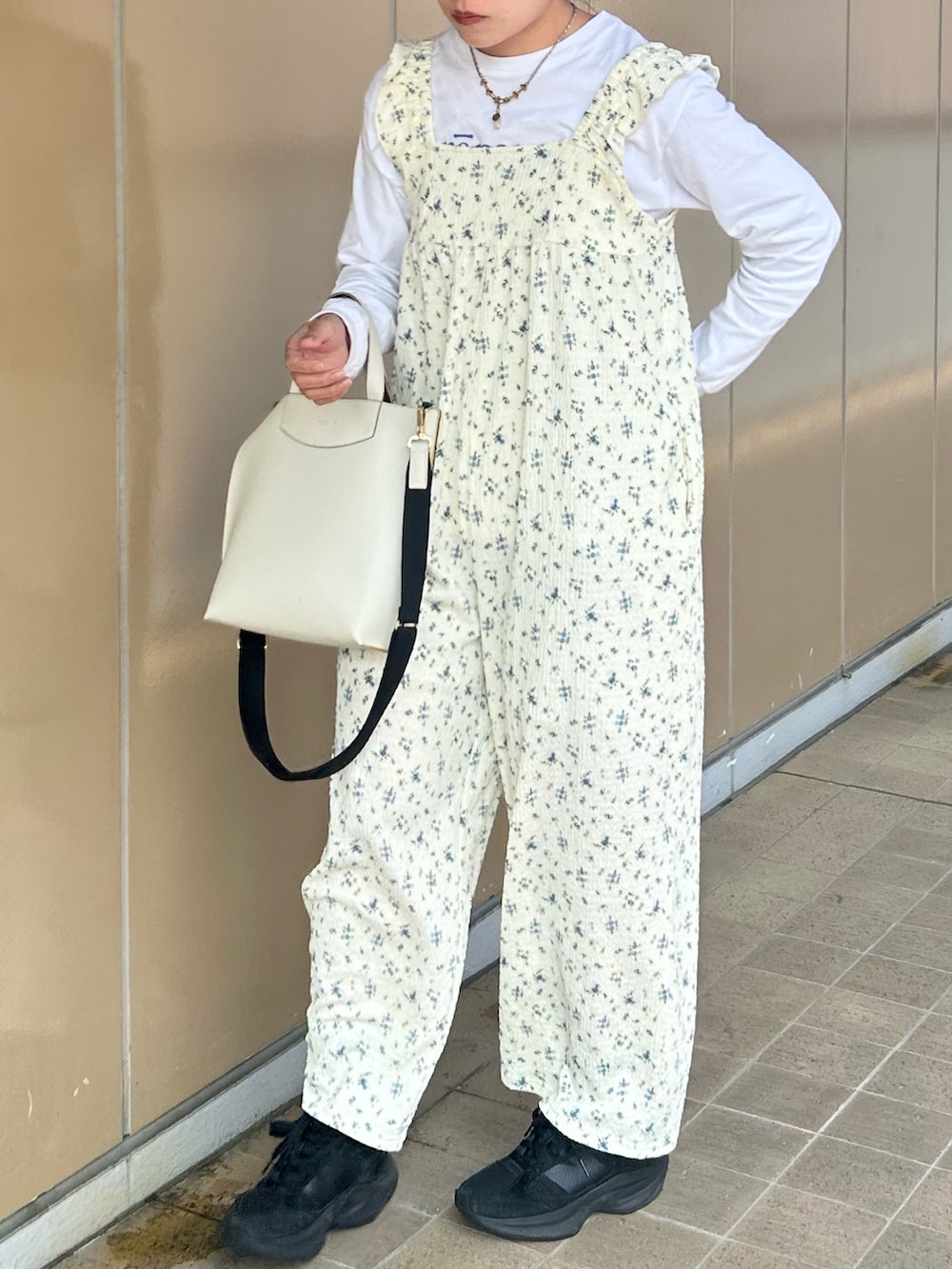 ブラック系のスニーカー、ホワイト系のTシャツ/カットソー、ホワイト系のオールインワン・サロペットを着用したレディースの春コーディネートの3枚目の写真