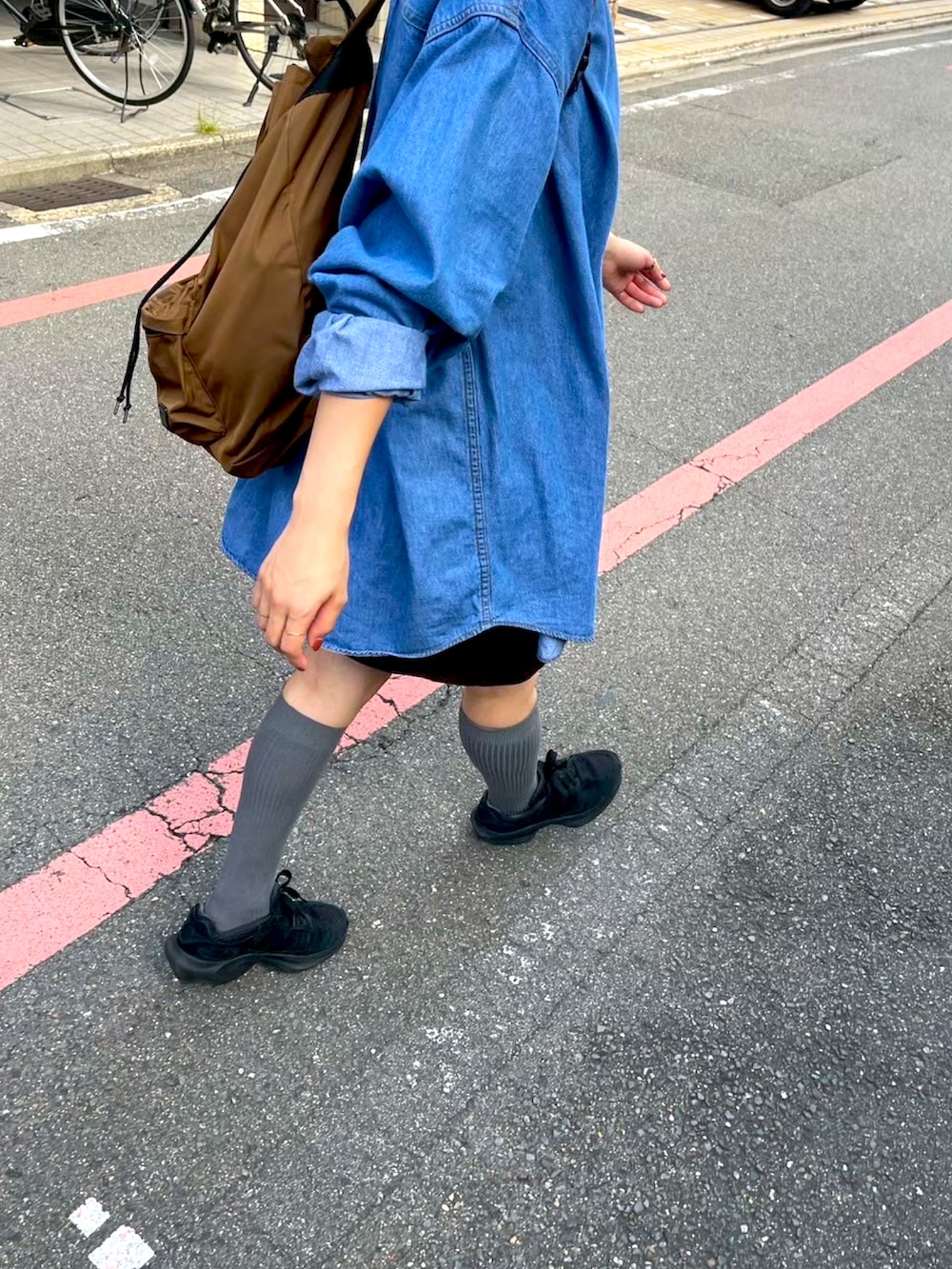 ブラック系のスニーカー、ブルー系のシャツ/ブラウス、ブラウン系のスカートを着用したレディースの春コーディネートの2枚目の写真