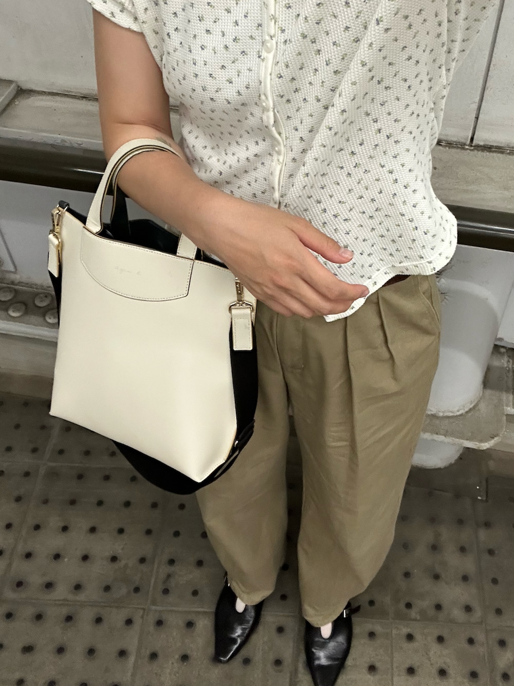 ブラック系のパンプス、ホワイト系のカーディガン/ボレロ、ベージュ系のチノパンツを着用したレディースの夏コーディネートの2枚目の写真