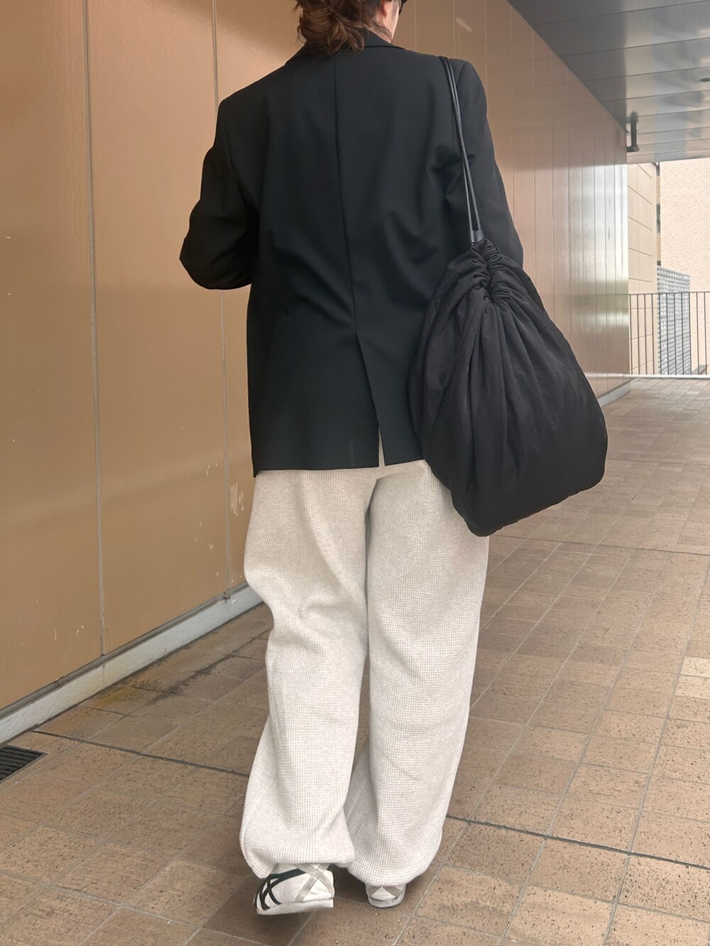 ホワイト系のスニーカー、グレー系のTシャツ/カットソー、ブラック系のテーラードジャケットを着用したレディースの春コーディネートの3枚目の写真