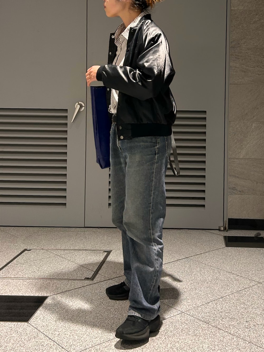 ブラック系のスニーカー、ブラック系のブルゾン、ブラック系のデニムパンツを着用したレディースの春コーディネートの3枚目の写真