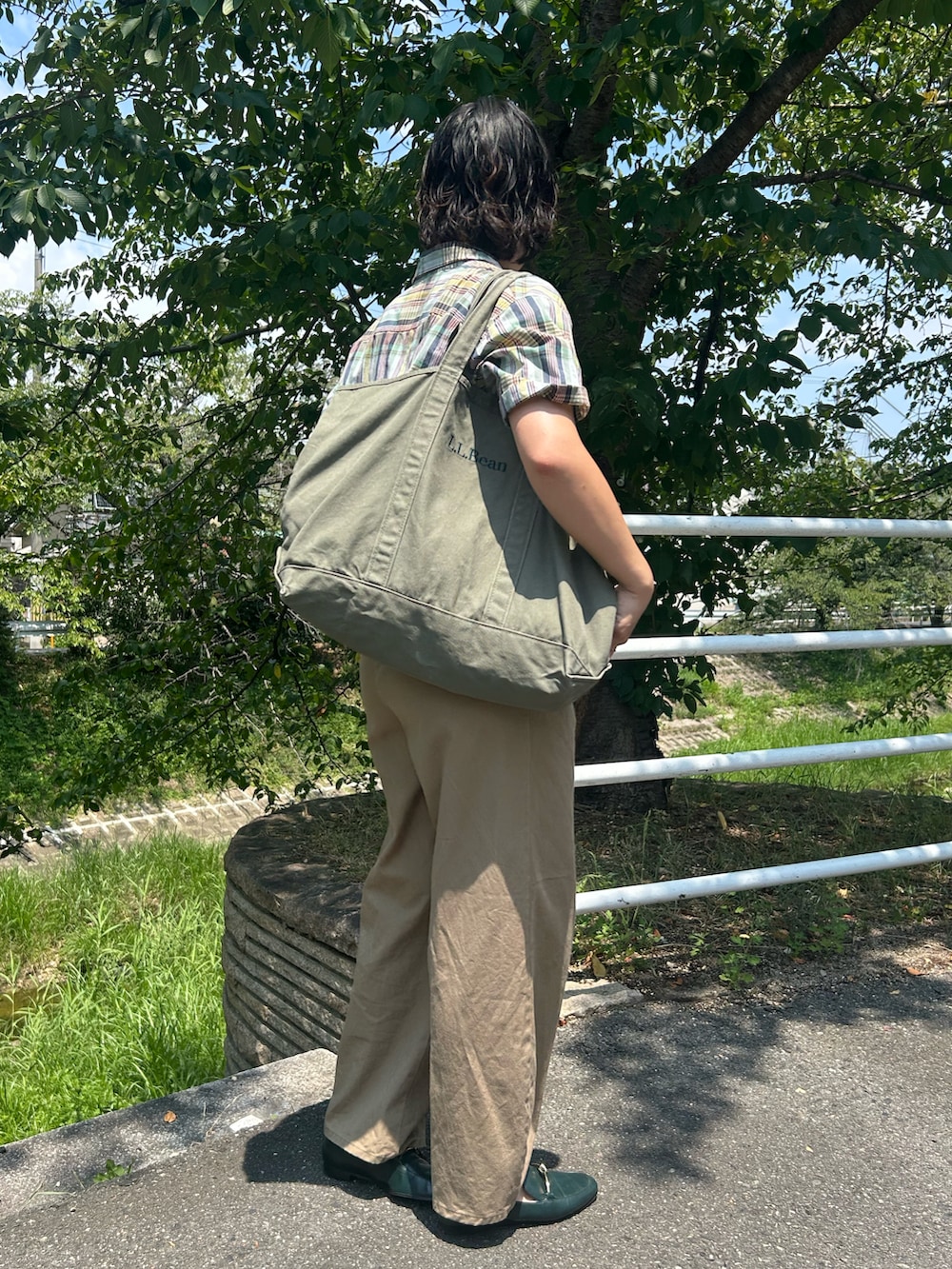 グリーン系のローファー、グリーン系のトートバッグ、ブルー系のシャツ/ブラウスを着用したレディースの夏コーディネートの3枚目の写真