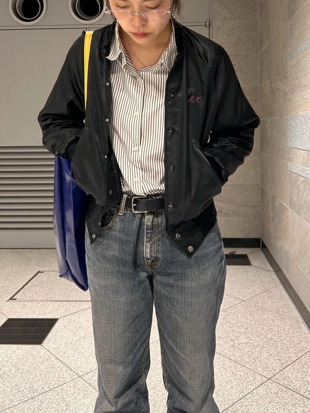 ブラック系のスニーカー、ブラック系のブルゾン、ブラック系のデニムパンツを着用したレディースの春コーディネートの5枚目の写真