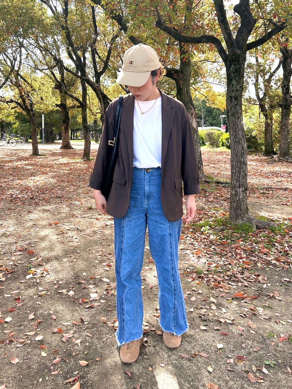 ブラウン系のテーラードジャケット、ベージュ系のスニーカー、ホワイト系のTシャツ/カットソーを着用したレディースの春コーディネートの2枚目の写真