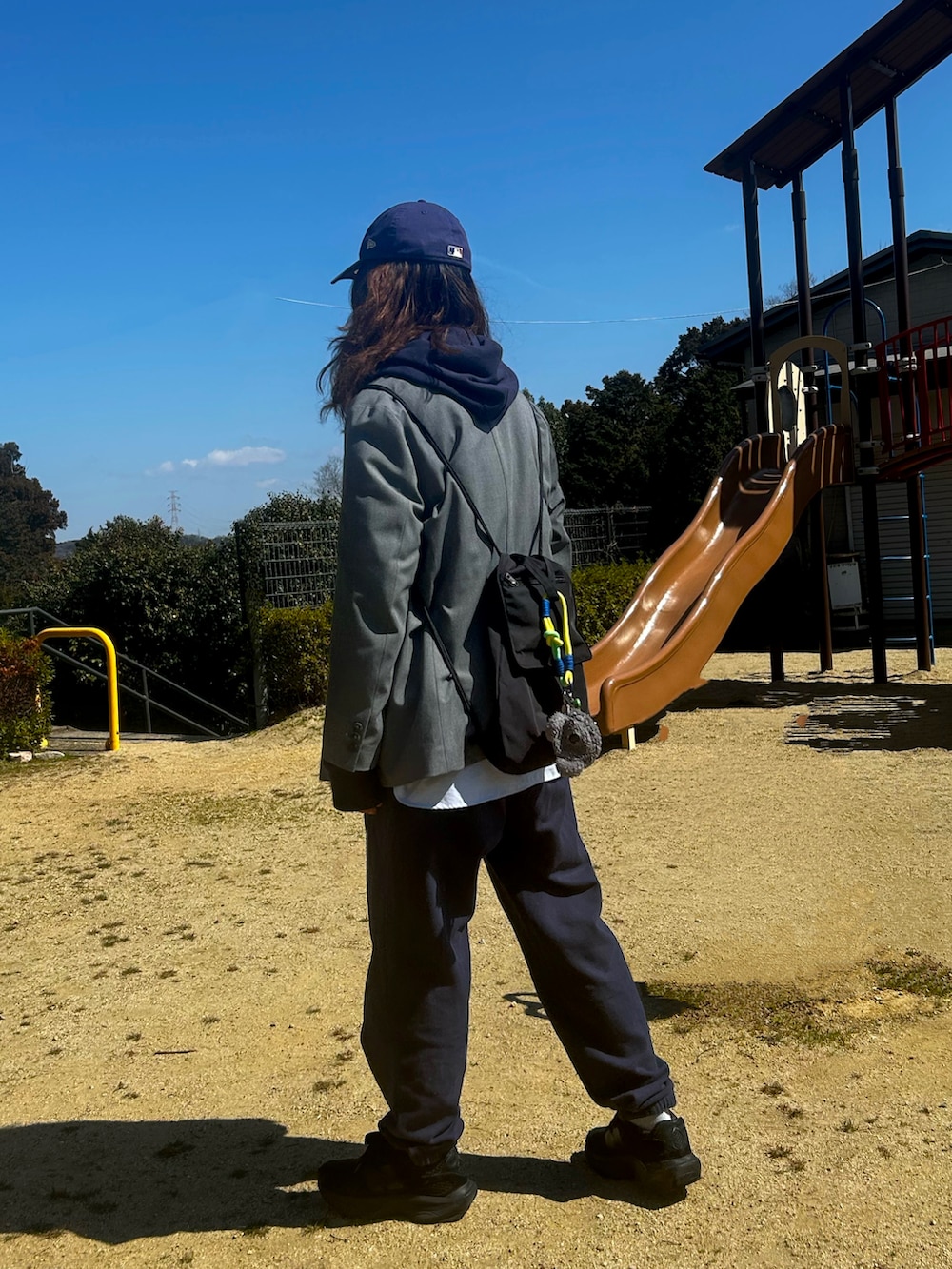 ブラック系のスニーカー、ブルー系のパーカー、グレー系のテーラードジャケットを着用したレディースの春コーディネートの2枚目の写真