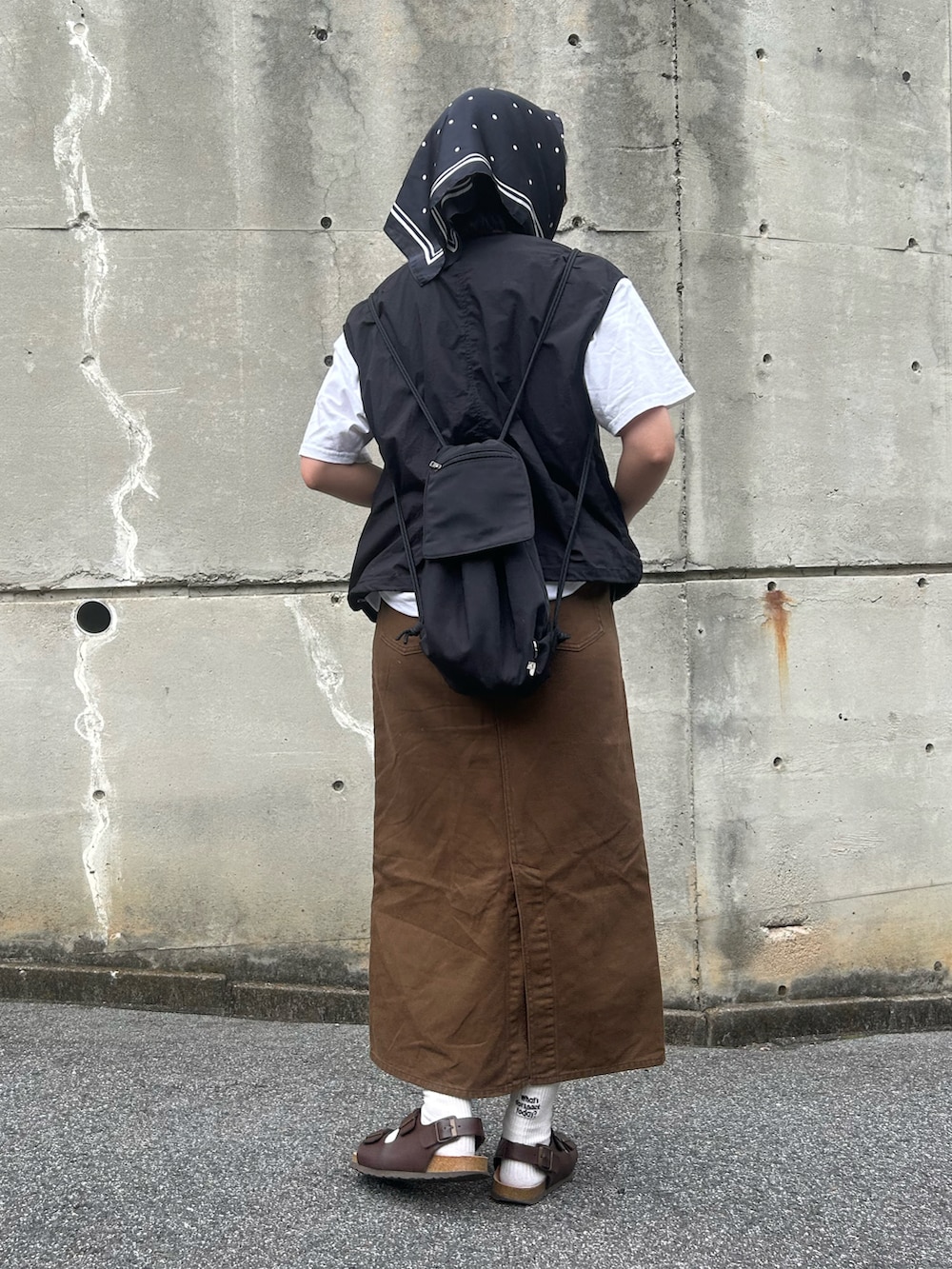 ブラック系のバックパック/リュック、ブラウン系のサンダル、ブラウン系のデニムスカートを着用したレディースの夏コーディネートの3枚目の写真