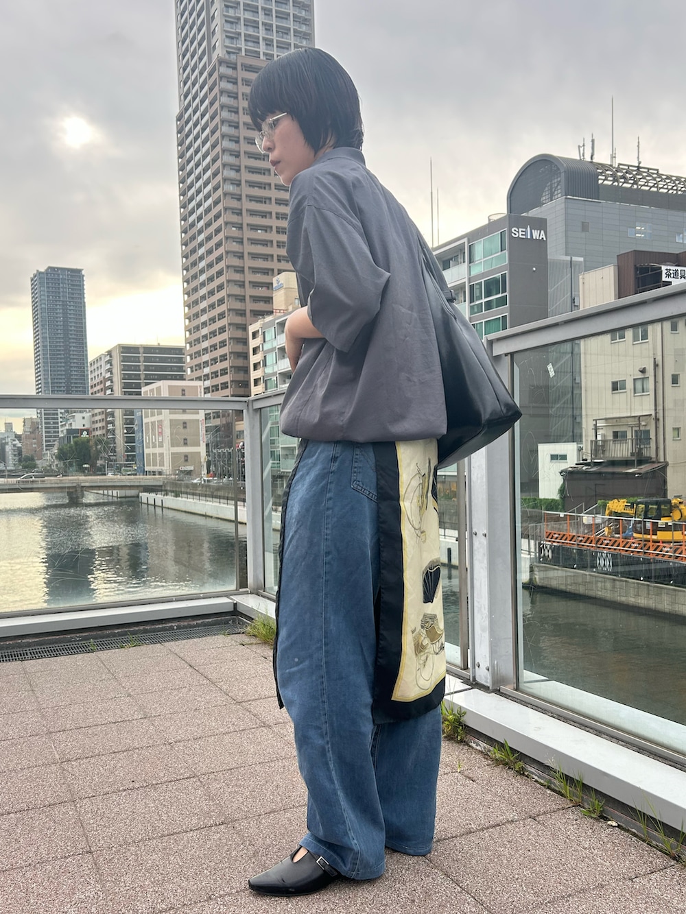 グレー系のポロシャツ、ブラック系のパンプス、ブラック系のバッグを着用したレディースの夏コーディネートの2枚目の写真