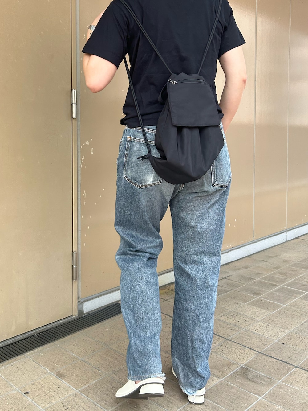 ブラック系のバックパック/リュック、ブラック系のTシャツ/カットソー、ホワイト系のサンダルを着用したレディースの夏コーディネートの3枚目の写真