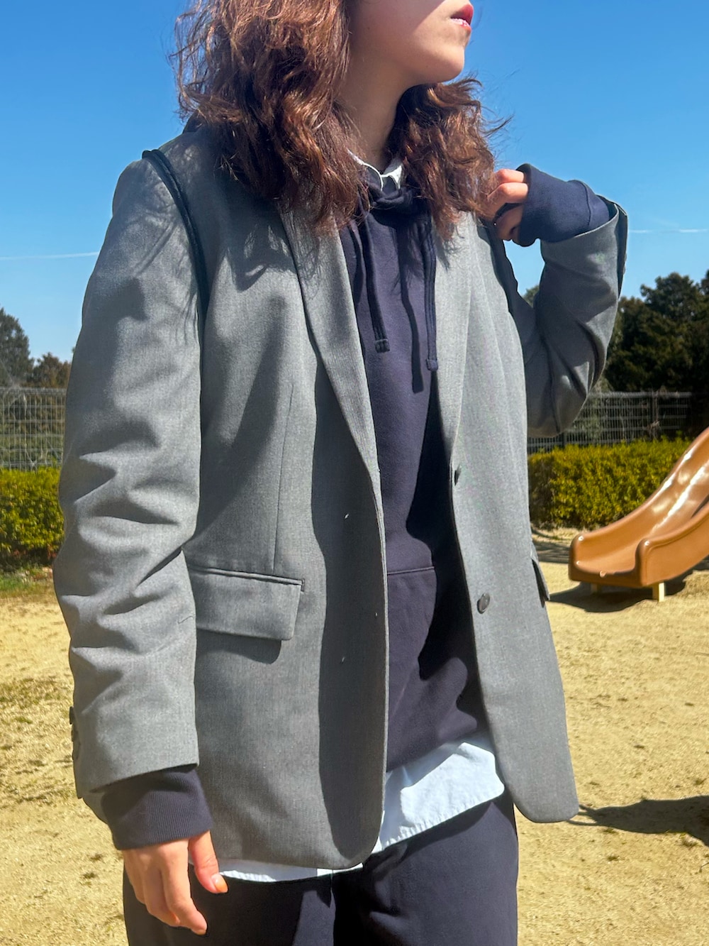 ブラック系のスニーカー、ブルー系のパーカー、グレー系のテーラードジャケットを着用したレディースの春コーディネートの3枚目の写真