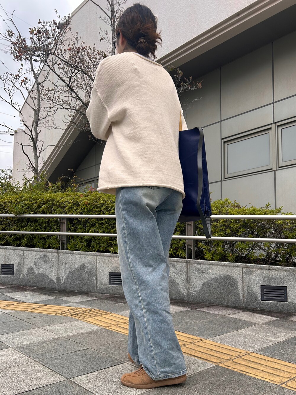 ブラウン系のスニーカー、ホワイト系のニット/セーター、ブルー系のデニムパンツを着用したレディースの春コーディネートの3枚目の写真