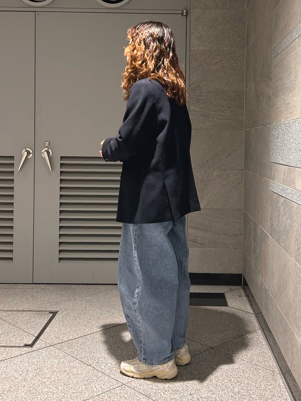 ベージュ系のトップス、ブルー系のテーラードジャケット、ブルー系のデニムパンツを着用したレディースの春コーディネートの3枚目の写真