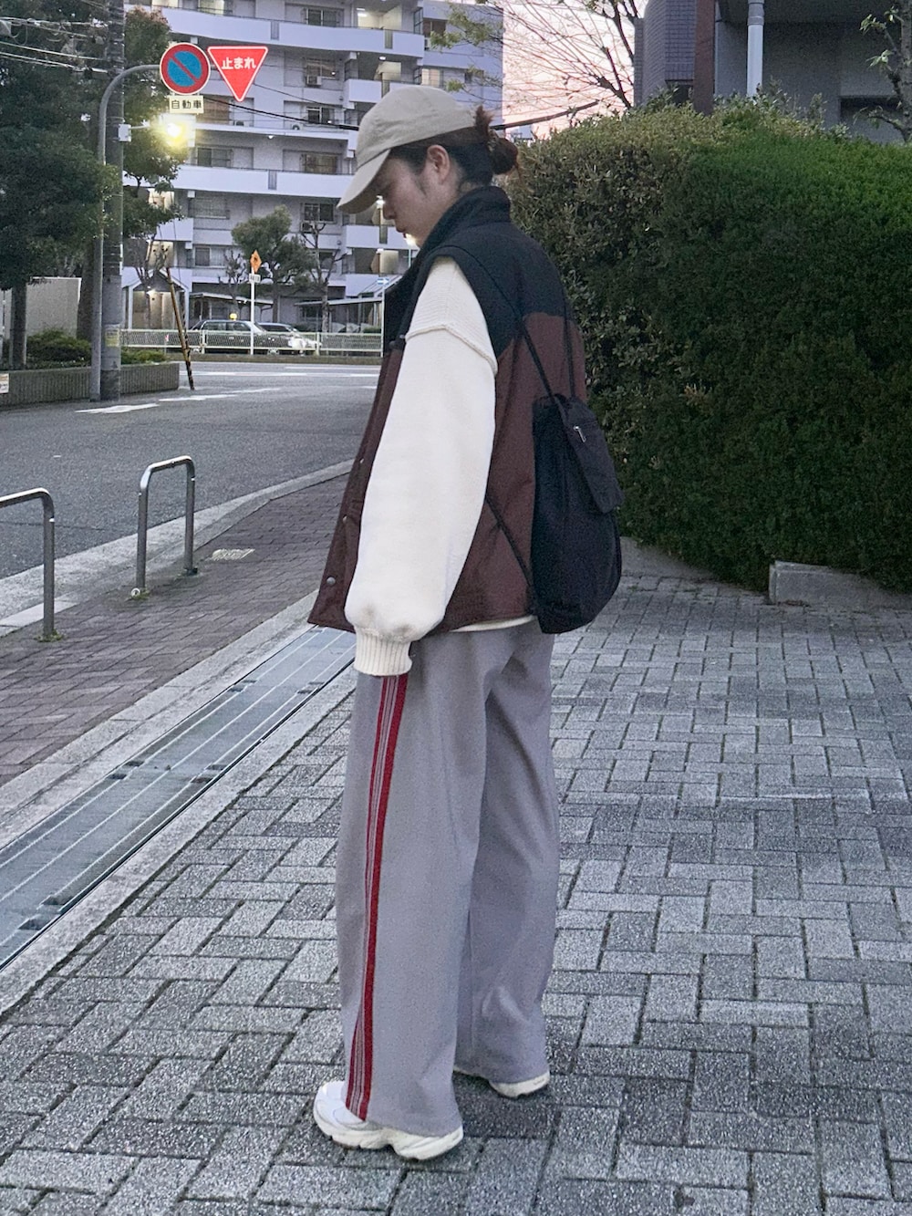 グレー系のその他パンツ、ホワイト系のニット/セーター、ベージュ系のスニーカーを着用したレディースの春コーディネートの2枚目の写真