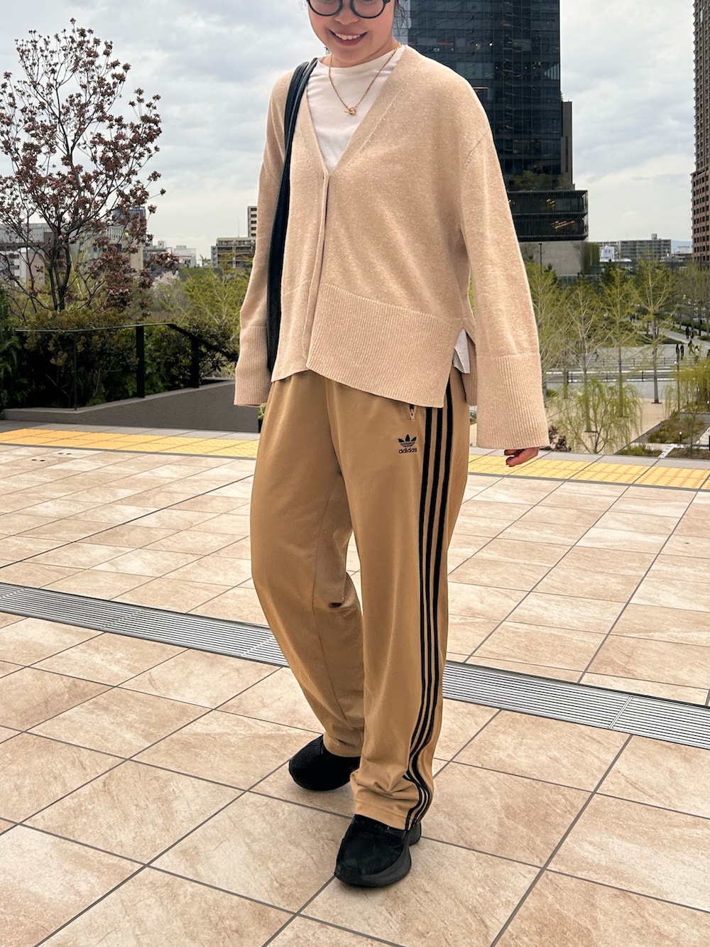 ホワイト系のTシャツ/カットソー、ベージュ系のカーディガン/ボレロ、ブラック系のスニーカーを着用したレディースの春コーディネートの2枚目の写真