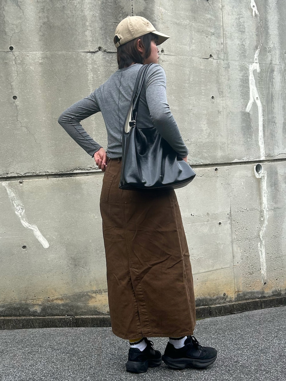 ブラウン系のデニムスカート、ブラック系のスニーカー、グレー系のTシャツ/カットソーを着用したレディースの夏コーディネートの2枚目の写真