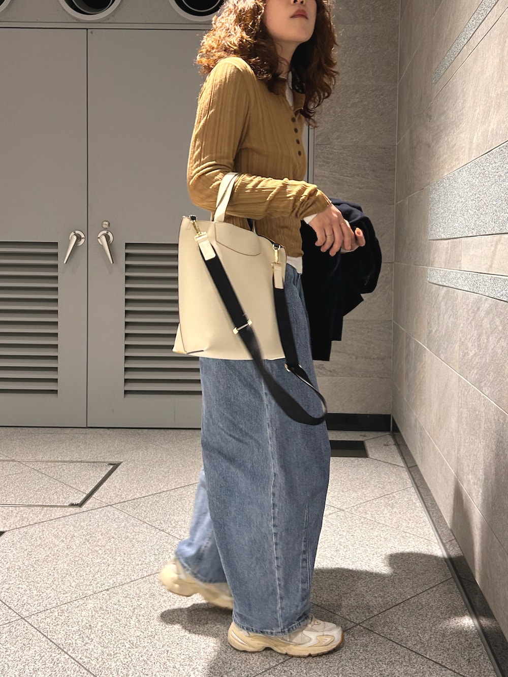 ベージュ系のトップス、ブルー系のテーラードジャケット、ブルー系のデニムパンツを着用したレディースの春コーディネートの4枚目の写真