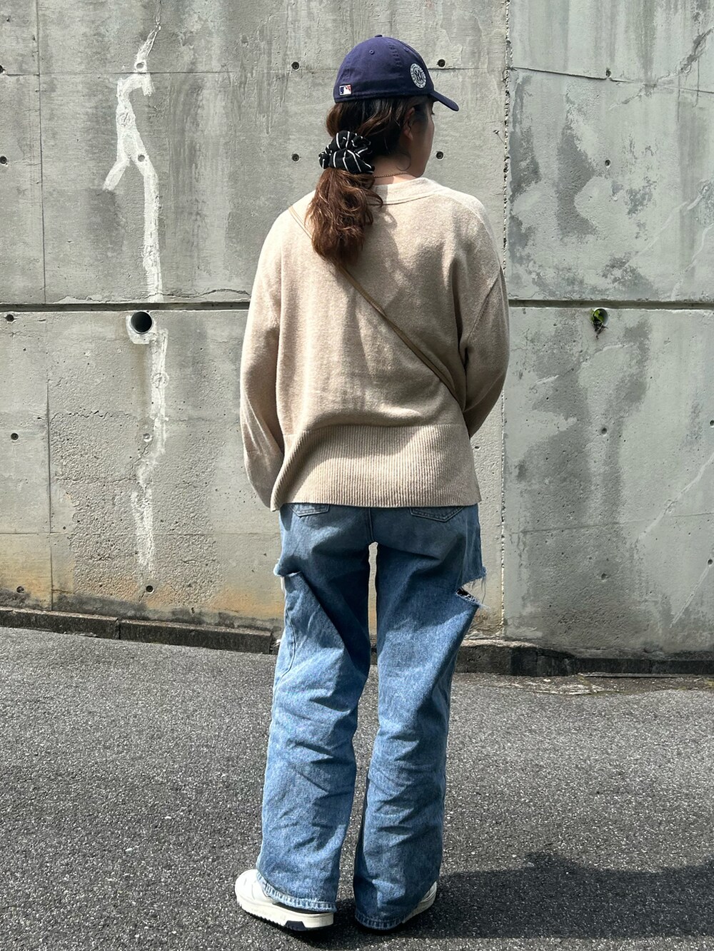ブルー系のデニムパンツ、ベージュ系のカーディガン/ボレロ、ホワイト系のスニーカーを着用したレディースの春コーディネートの3枚目の写真