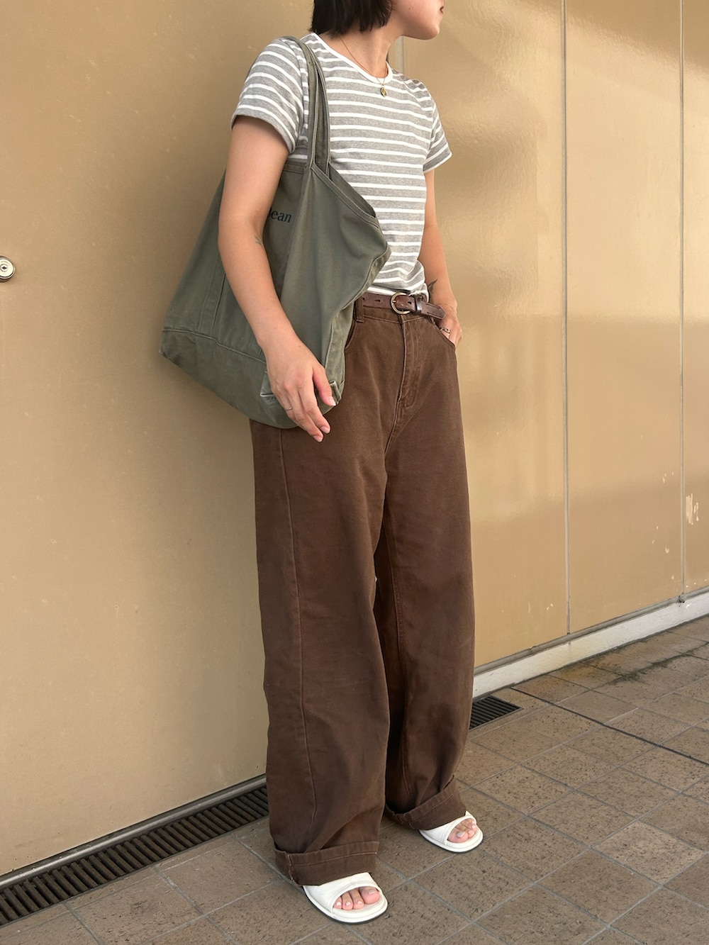 グリーン系のトートバッグ、ホワイト系のサンダル、グレー系のTシャツ/カットソーを着用したレディースの夏コーディネートの2枚目の写真
