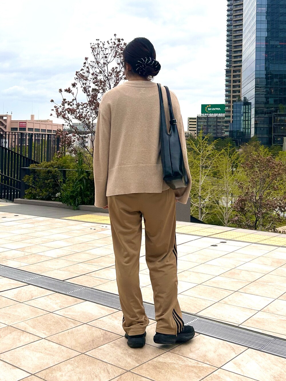 ホワイト系のTシャツ/カットソー、ベージュ系のカーディガン/ボレロ、ブラック系のスニーカーを着用したレディースの春コーディネートの5枚目の写真