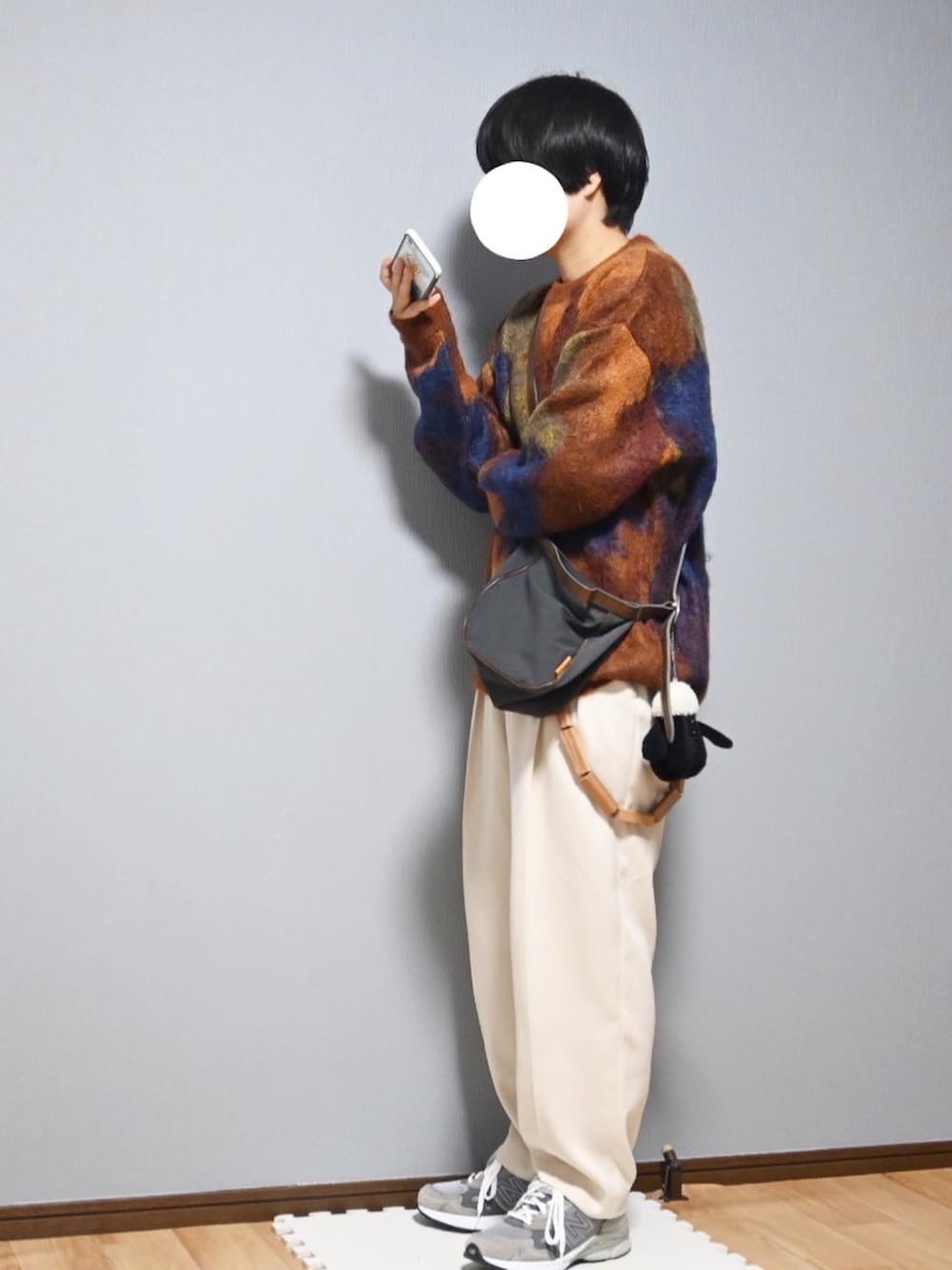 オレンジ系のニット/セーター、グレー系のショルダーバッグ、ホワイト系のスラックスを着用したレディースの秋コーディネートの2枚目の写真