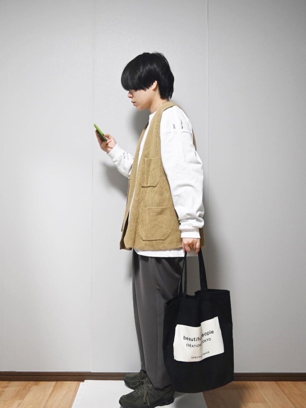 ホワイト系のTシャツ/カットソー、ベージュ系のベスト、ブラウン系のスラックスを着用したレディースの春コーディネートの2枚目の写真