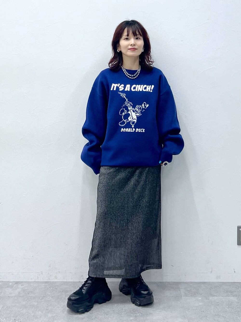 ブラック系のブーツ、ブラック系のスカート、ブルー系のニット/セーターを着用したレディースの冬コーディネートの2枚目の写真