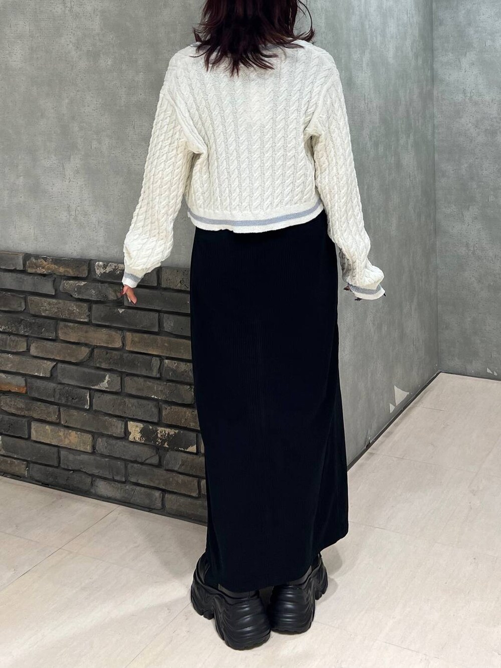 ブラック系のブーツ、ブラック系のスカート、ホワイト系のカーディガン/ボレロを着用したレディースの冬コーディネートの4枚目の写真