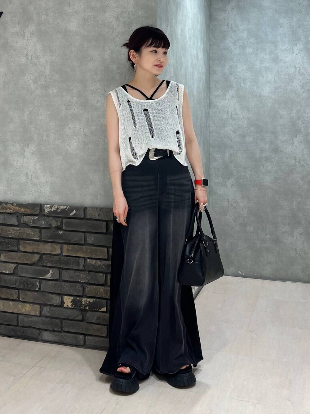 ブラック系のデニムパンツ、ブラック系のショルダーバッグ、ホワイト系のベストを着用したレディースの夏コーディネートの7枚目の写真