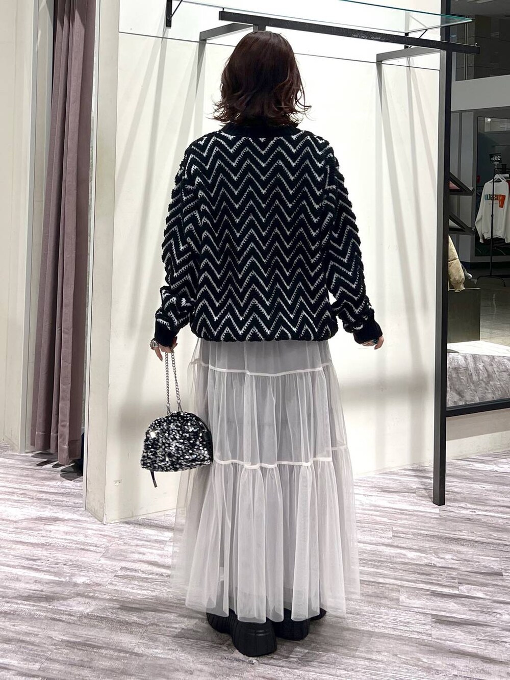 ブラック系のブーツ、シルバー系のショルダーバッグ、ブラック系のニット/セーターを着用したレディースの冬コーディネートの4枚目の写真