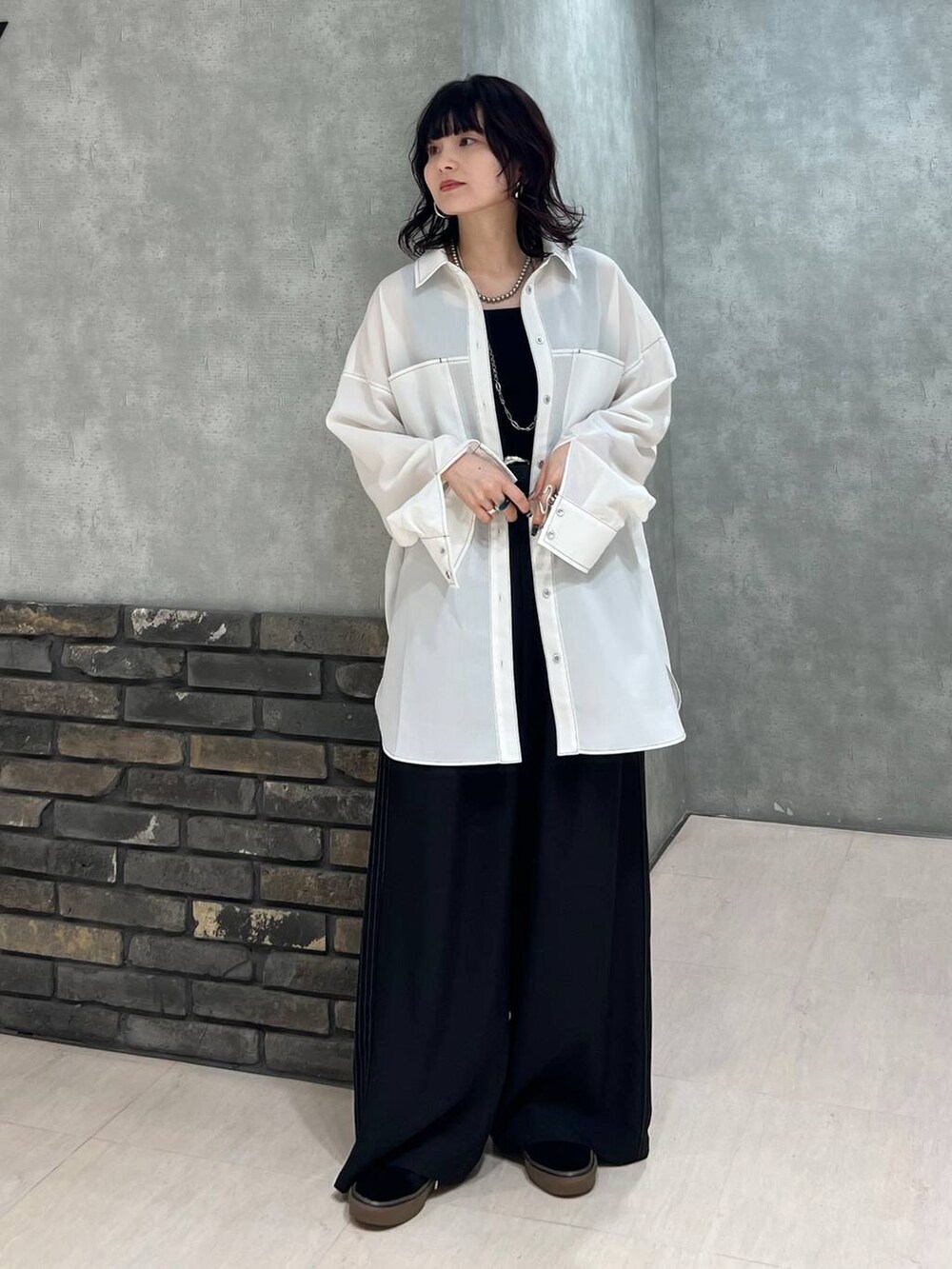 ブラック系のスラックス、ブラック系のタンクトップ、ブラック系のベルトを着用したレディースの春コーディネートの2枚目の写真