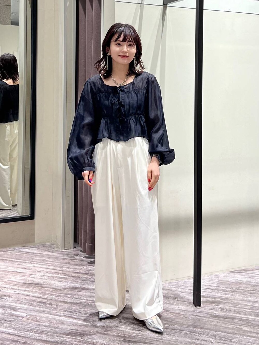 シルバー系のパンプス、ホワイト系のスラックス、ブラック系のシャツ/ブラウスを着用したレディースの春コーディネートの2枚目の写真