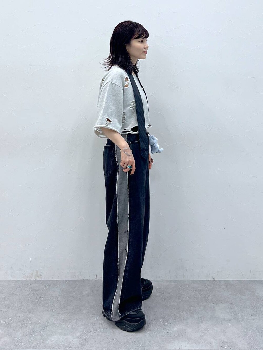 グレー系のネクタイ、ブラック系のスニーカー、ブルー系のデニムパンツを着用したレディースの夏コーディネートの3枚目の写真