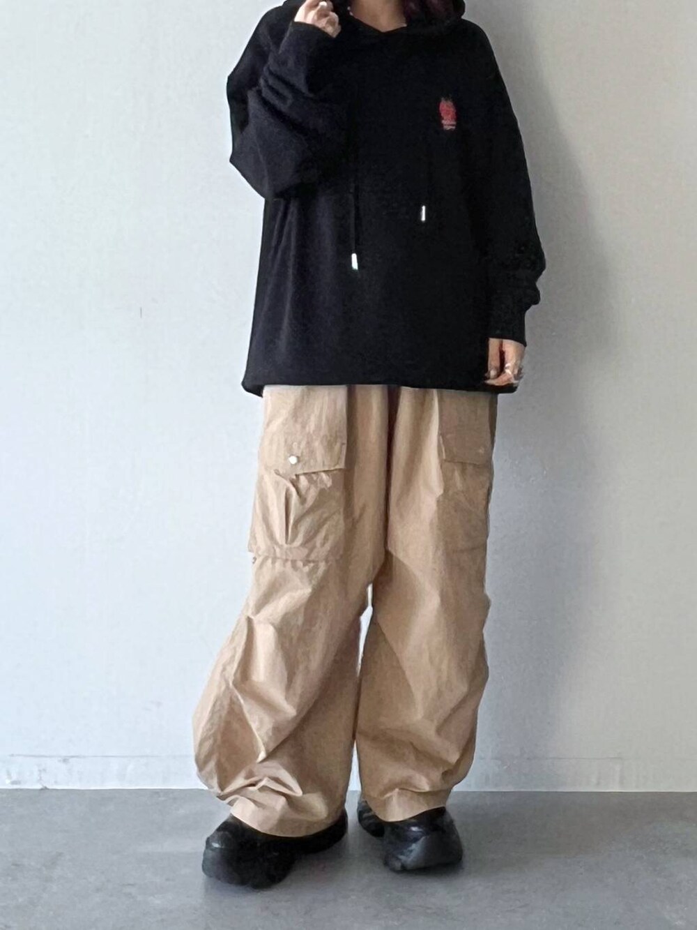 ブラック系のスニーカー、ベージュ系のカーゴパンツ、ブラック系のパーカーを着用したレディースの夏コーディネートの5枚目の写真