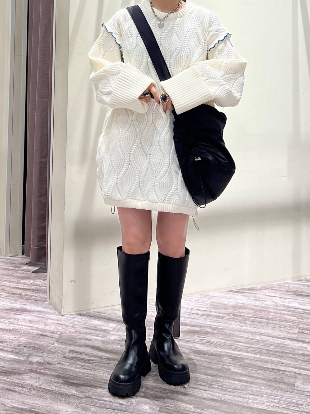 ブラック系のブーツ、ブラック系のショルダーバッグ、ホワイト系のニット/セーターを着用したレディースの冬コーディネートの7枚目の写真