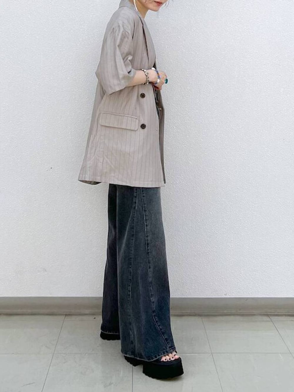 ブラック系のデニムパンツ、ブラック系のサンダル、ブラウン系のテーラードジャケットを着用したレディースの秋コーディネートの5枚目の写真