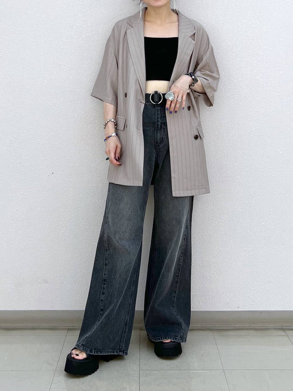 ブラック系のデニムパンツ、ブラック系のサンダル、ブラウン系のテーラードジャケットを着用したレディースの秋コーディネートの6枚目の写真