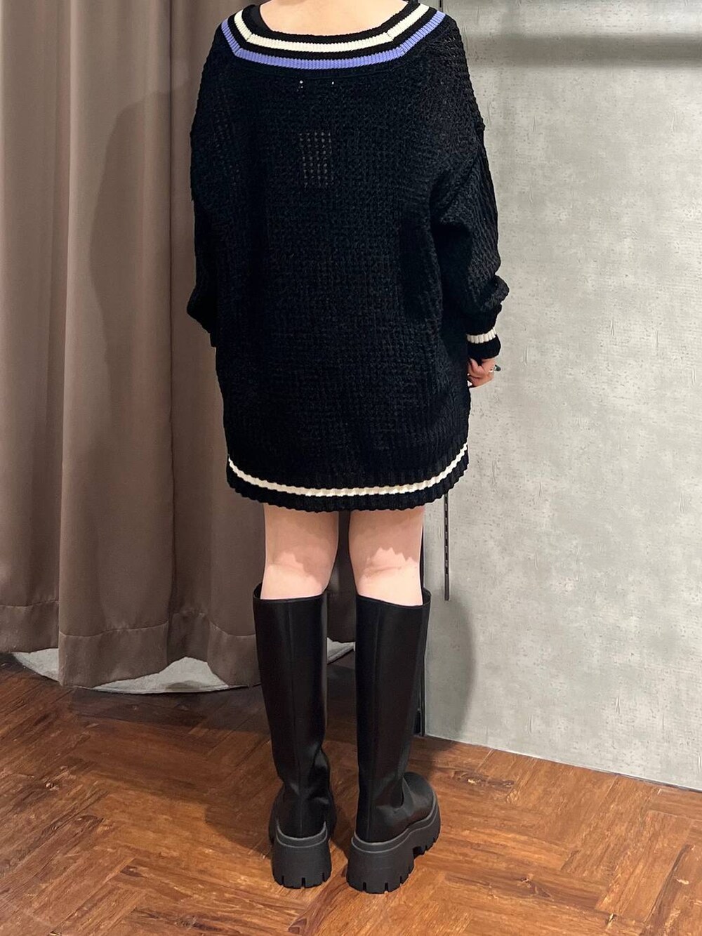 ブラック系のニット/セーター、ブラック系のスカート、ブラック系のブーツを着用したレディースの秋コーディネートの4枚目の写真