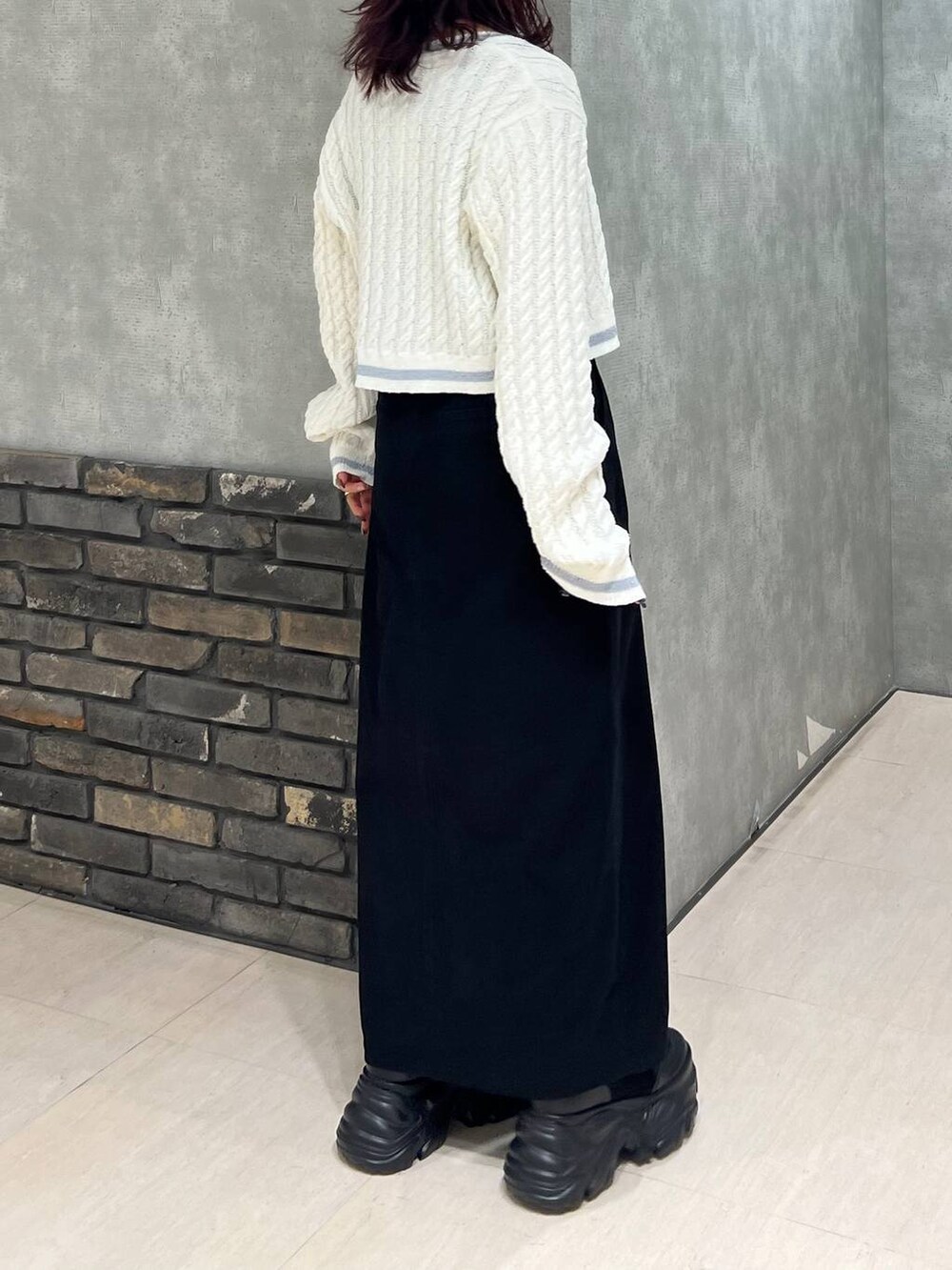 ブラック系のブーツ、ブラック系のスカート、ホワイト系のカーディガン/ボレロを着用したレディースの冬コーディネートの5枚目の写真