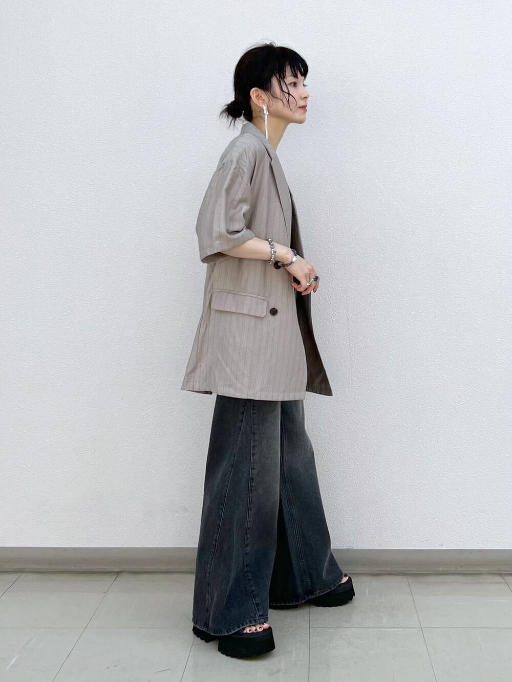 ブラック系のデニムパンツ、ブラック系のサンダル、ブラウン系のテーラードジャケットを着用したレディースの秋コーディネートの3枚目の写真