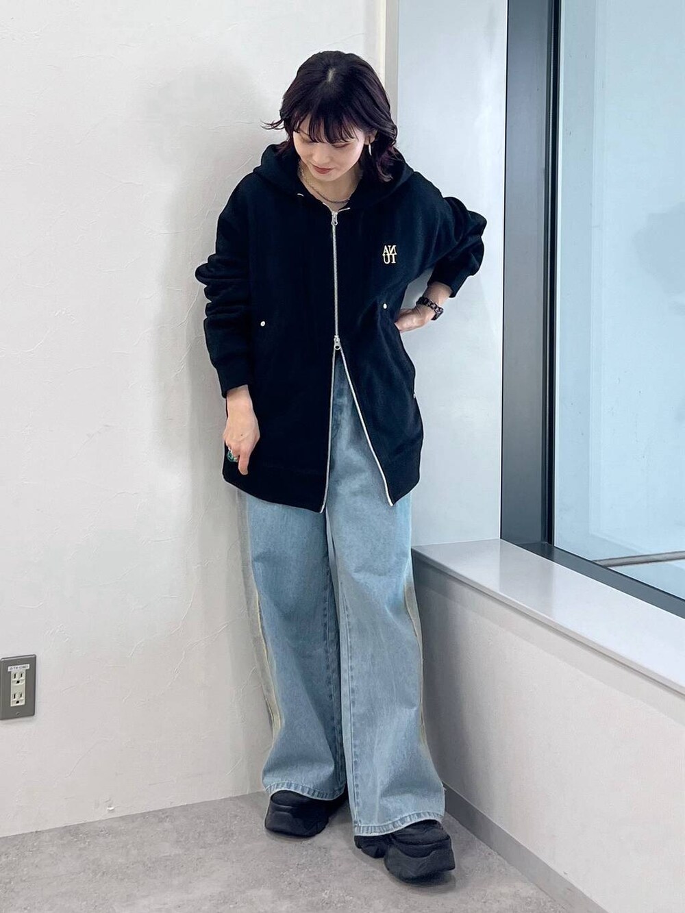 ブラック系のパーカー、ブラック系のスニーカー、ブルー系のデニムパンツを着用したレディースの冬コーディネートの2枚目の写真