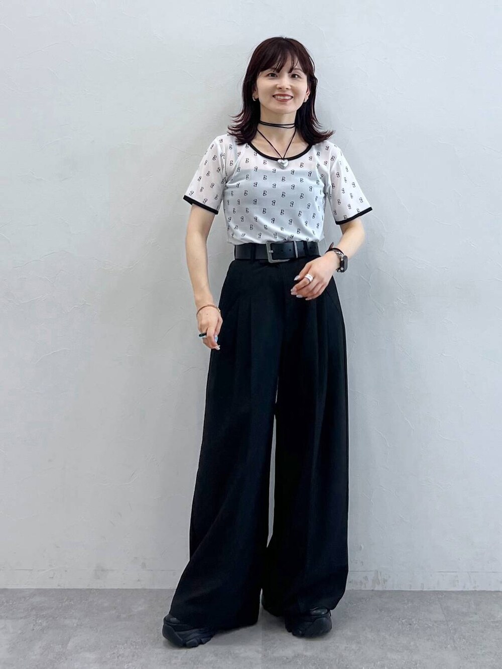 ブラック系のスニーカー、ホワイト系のTシャツ/カットソー、ブラック系のスラックスを着用したレディースの夏コーディネートの2枚目の写真